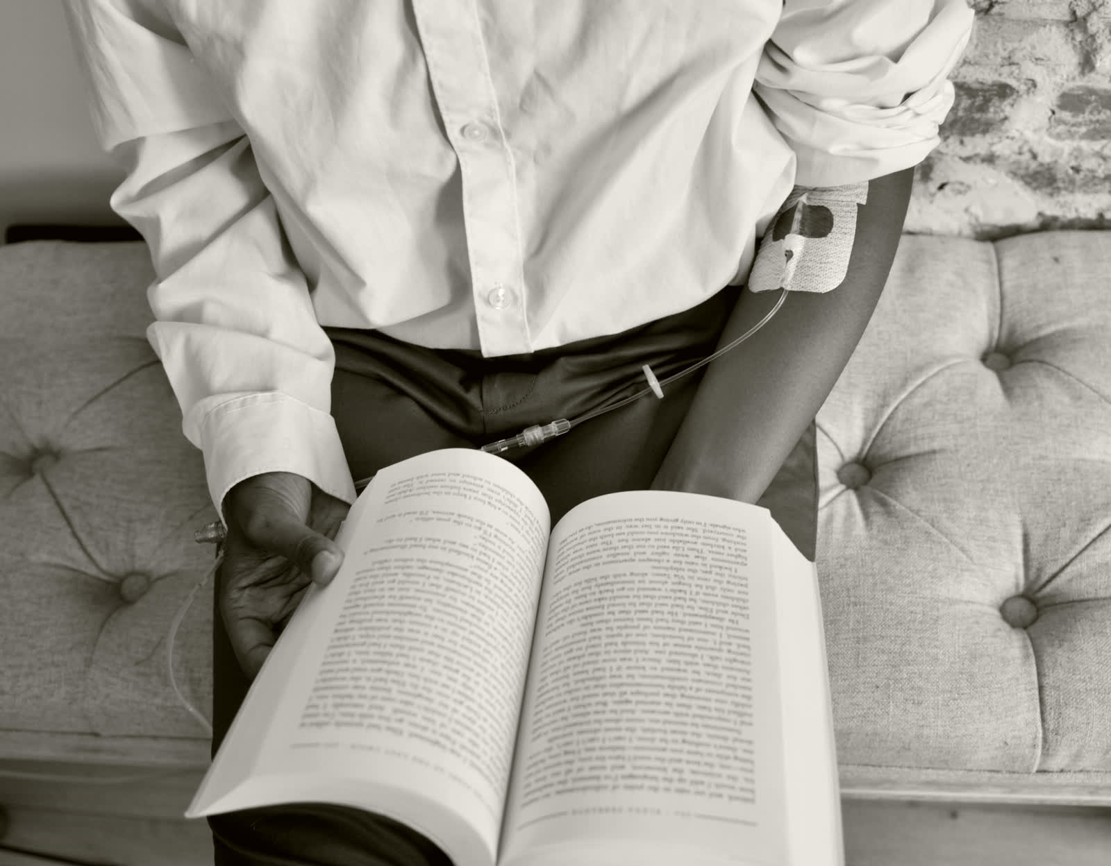A client reading quietly while receiving an infusion